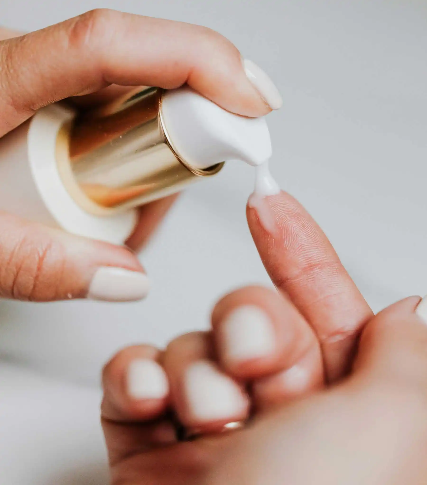 Mulher aplicando creme hidratante no rosto em ambiente calmo e iluminado
